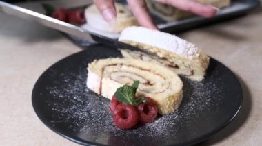 şef ortaya koyar ve doğranmış İsviçre rulo süsler. Ahududu ile süslenmiş İsviçre Rulosu.