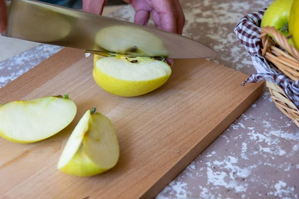 Frau schneidet mit Messer einen Apfel in Scheiben auf einem Schneidebrett auf einem T — Stockfoto