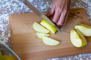 Bir t üzerinde bir kesme tahtasında dilimleri için bıçak bir elma tarafından kadın keser