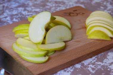 Mutfakta bir masada bir kesme tahtasında bıçak ve elma. Caner