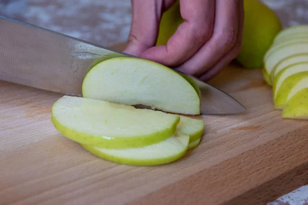 Frau schneidet mit Messer einen Apfel in Scheiben auf einem Schneidebrett auf einem T — Stockfoto