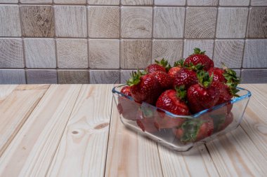 açık ahşap masada çilek ile kare cam kase