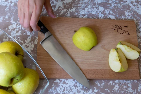 Frau schneidet mit Messer einen Apfel in Scheiben auf einem Schneidebrett auf einem T — Stockfoto