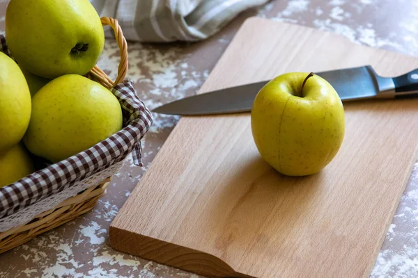 Messer und Apfel auf einem Schneidebrett auf einem Tisch in der Küche. ch — Stockfoto