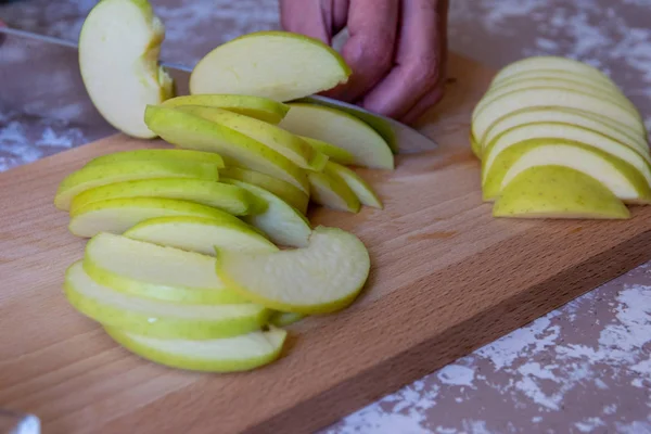 Frau schneidet mit Messer einen Apfel in Scheiben auf einem Schneidebrett auf einem T — Stockfoto