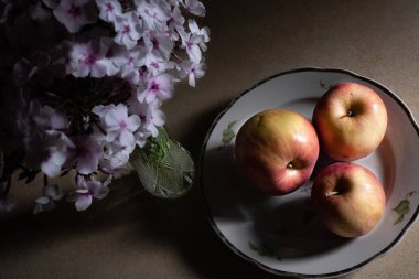 Mutfaktaki masada tabakta üç elma ve phlox var. Düşük