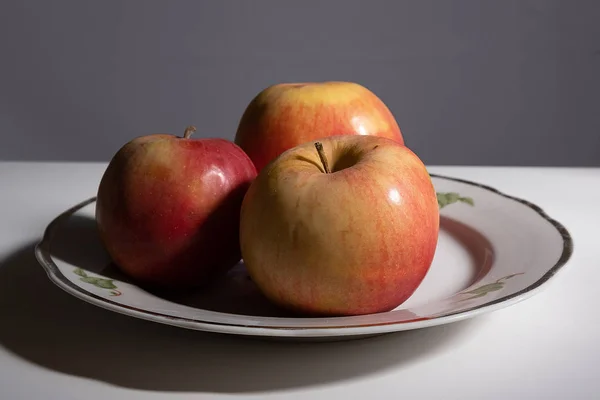 แอปเปิ้ลสามลูกบนจานบนโต๊ะในครัว กุญแจต่ํา — ภาพถ่ายสต็อก