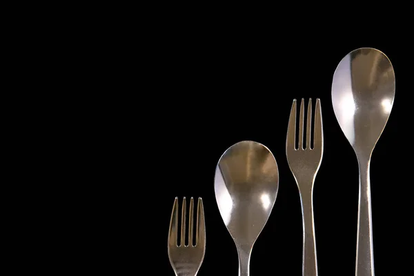 Metal forks and spoons on a black background. top view on stainl — Stock Photo, Image