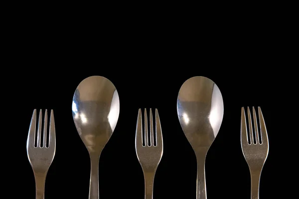 Metal forks and spoons on a black background. top view on stainl — Stock Photo, Image