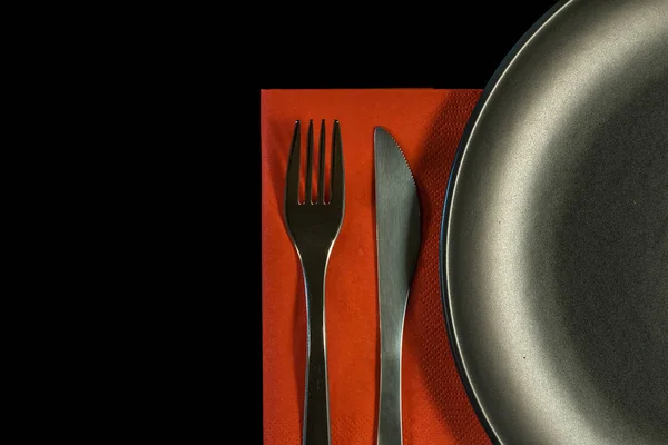 金属叉，红色餐巾上的刀和黑色背景的盘子. — 图库照片