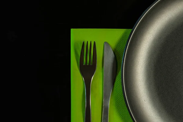 金属叉，绿色餐巾上的刀和黑色背毛板上的盘子 — 图库照片