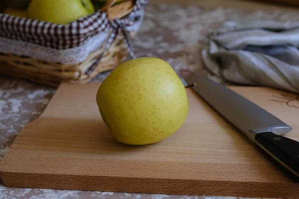 Coltello e mela su un tagliere su un tavolo in cucina. Ch — Foto Stock