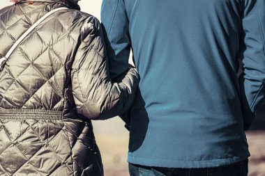 Yaşlı bir çift kolundan tutup caddede yürür. Arka plan.