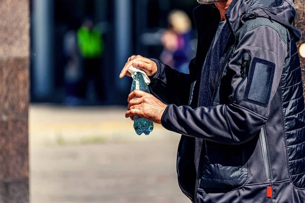 Bir adam mendille siliyor. Güneşli bir günde şehrin caddesindeki bir dükkandan alınmış bir su şişesi..