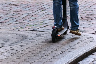 Baharda e-scooter sürmek. Çocuk elektrikli scooter kullanıyor, kaldırımda bacakları var.. 