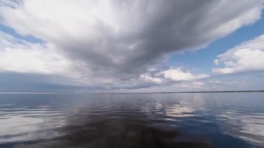 Gün batımında deniz üzerinde hareket eden düşük seviyeli beyaz bulutlar. Su saatindeki bulutların yansıması..