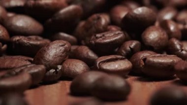 Kavrulmuş kahve çekirdeklerinin aşırı yakın çekimi. Düşen kahve çekirdeklerini yavaş çekimde canlandırma videosu.
