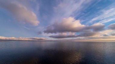 Gün batımında alçak bulutların inanılmaz hareketi. Gök kabarık beyaz bulutlarla gölün zaman akışının üzerine.