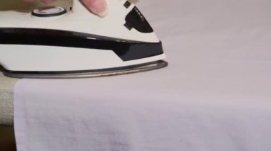 Ev hanımı evde beyaz gömlek ütülüyor, yakın plan. Çamaşır günü