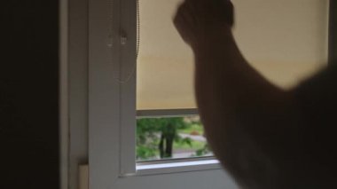 Kadın perdeleri açıyor. Patenli külüstür arabalı bir pencere. Penceredeki sarı lombozlar.