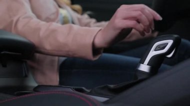 Kadının elleri yeni arabasının vites kolunu değiştiriyor. Arabayı kız kullanıyor..