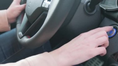 Modern arabanın içinde, bir kadının eli motoru çalıştırma düğmesine basar. Arabayı süren kız..