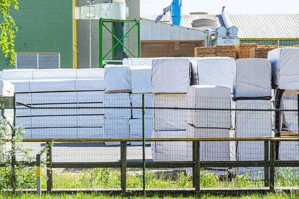 Rows of white packed boxes with materials or finished products in an open-air warehouse area.