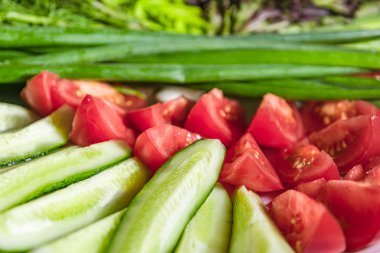 Renkli sebze dilimleri. Beyaz tabakta çiğ domates ve salatalık dilimleri. Vejetaryen yemeği..