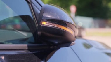 Modern bir arabanın yan aynasını otomatik olarak katlıyor. Dikiz aynasında sinyal yanıp sönüyor..