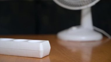 Kadın fişi takıyor ve evdeki vantilatörü açıyor. Hayranı olan kadın.