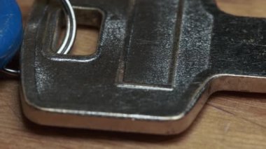 Ahşap bir masada mavi bir anahtarlığın eski gümüş anahtarının yakın çekimi..