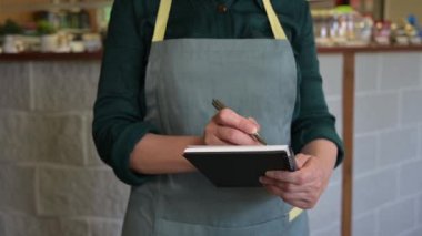 Garson kafedeki müşterilerden sipariş alır. Başarılı küçük işletme sahibi, günlük gri önlük giyiyor..