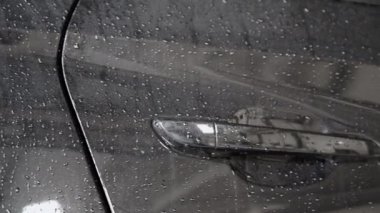 Kapıya su damlalarını yakın çekim yap ve arabanın sapını tut. Araba yıkanıyor..