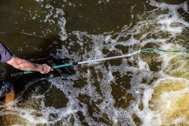 Bir adamın eli nehrin girdabında kelebek ağıyla balık yakalar..