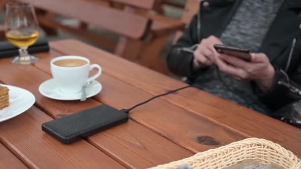 여자가 커피숍에서 충전을 휴대폰을 은행에 — 비디오