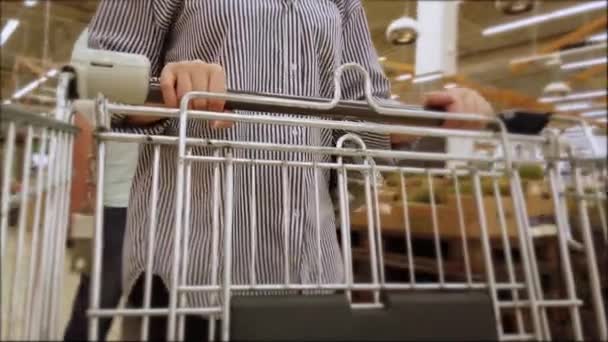 超市里的女店员推着空的金属购物车 在杂货店买东西 — 图库视频影像