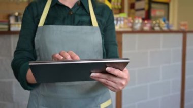 Bayan garson, küçük bir kafede tablet kullanan bir müşteriden sipariş alır..