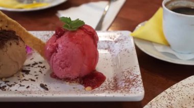 Kafedeki bir masada bir porsiyon dondurma. Ahududu ve Kahveli Dondurma.