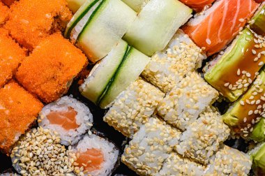 Suşi ve rulo şeklinde arka plan, restoran teslimatı yakın plan. Somonlu Maki, unagi, balıklı sağlıklı yemekler.