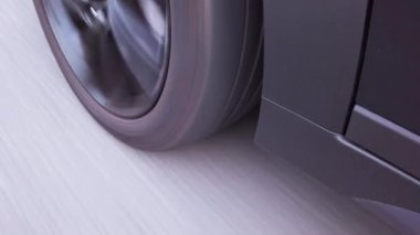 Asfalt yolda giden bir yolcu aracının ön tekerleğine yakın çekim..