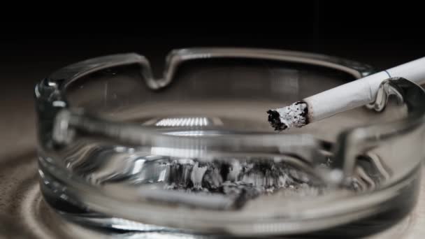 在典型的玻璃烟灰缸边缘燃烧着的香烟 停止吸烟 — 图库视频影像