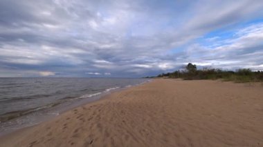 Sonbaharın başında terk edilmiş kumlu deniz plajı. Güzel mavi gökyüzü Denizde beyaz bulutlar.