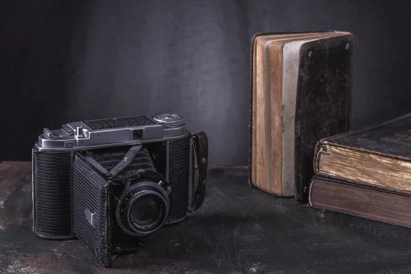 Old rare books and camera in black hardcover.