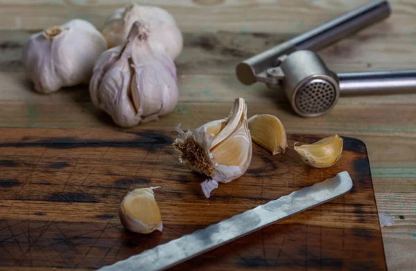 Garlic and garlic press in the kitchen on the board.
