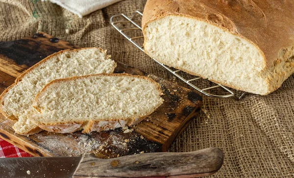 Homemade bread. Homemade pastries. Made from wheat flour. Tasty and healthy. Fresh bread on the kitchen table. For vegetarians. A loaf on the table. Slice of bread. On a chopping board.