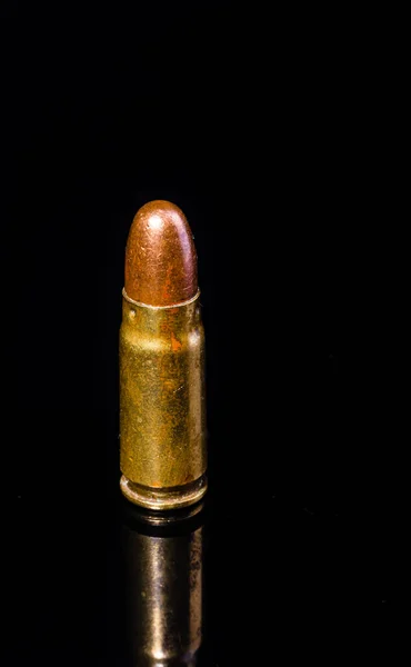 Pistol bullet. Metal case. Old ammunition. Cartridge on a black background. Macro shot of a bullet. Isolated from background. Armaments and defense. Self-defense tools.