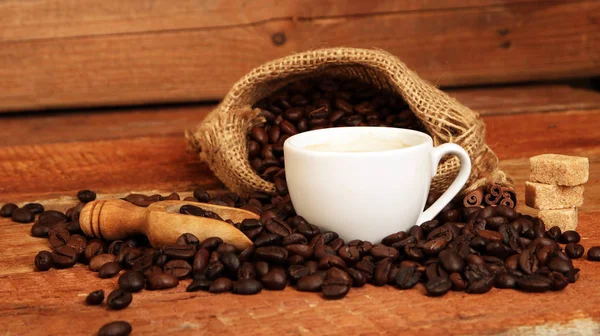 Cangkir kopi dengan biji kopi, karung goni dan dengan tongkat kayu manis — Stok Foto