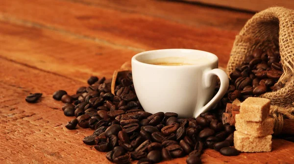 Taza de café con granos de café, saco de arpillera y con palitos de canela —  Fotos de Stock