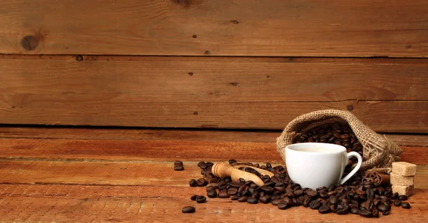 Taza de café con granos de café, saco de arpillera y con palitos de canela —  Fotos de Stock