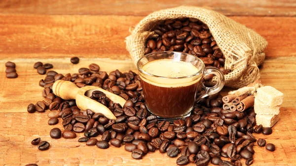 Taza de café con granos de café, saco de arpillera y con palitos de canela —  Fotos de Stock